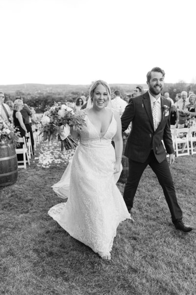 couple exits outdoor wedding ceremony smiling as newlyweds in upstate new york