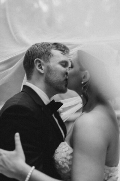 Bride and groom kissing under the veil