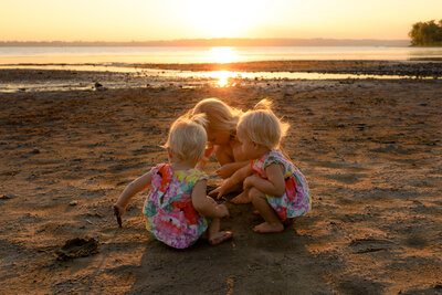 A young girl and her two toddler sisters playing at the beach with a view of the Gatineau Ottawa River