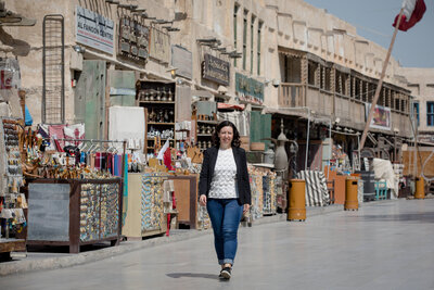 Show thumbnail preview	 A woman walks down a street market lined with various shops and stalls on a sunny day, reflecting on her journey in educational leadership.