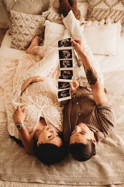 A couple snuggles together while basking in their joy during a maternity studio session with Nikii Pix Photography.