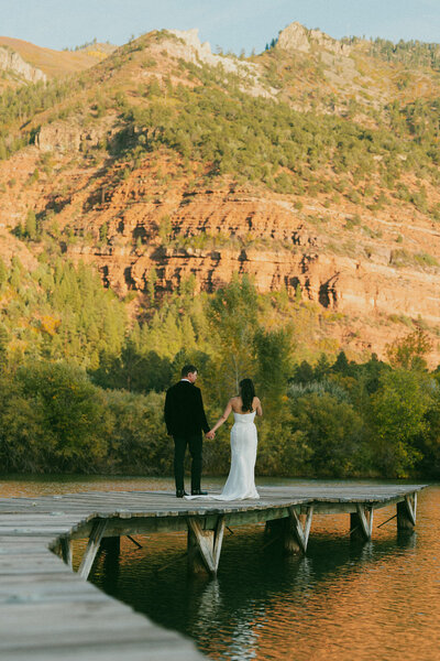 bride and groom on bridge over lake