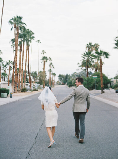 Bride and groom walking away from the camera down the road in Palm Springs
