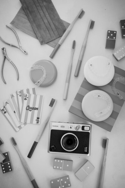 Black and white flatlay of a vintage film camera and an assortment of orthodontic tools