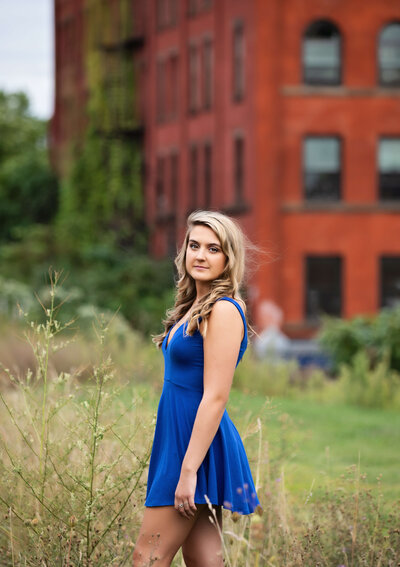 Erie Pa senior girl in a blue dress in a grassy area by the PACA in downtown