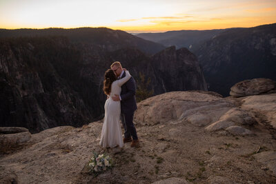 A bride and groom kiss after their elopement ceremony in Yosemite as the sunsets behind them.