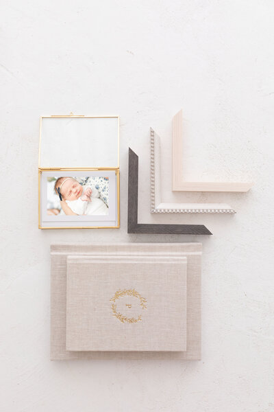 newborn proof prints in a glass box with albums and frame corners