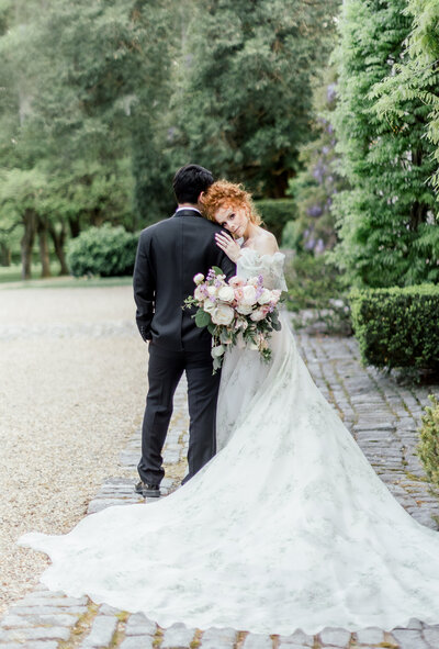 a bride and groom embracing while wrapped in a wedding veil