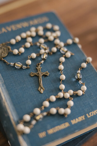 Rosary beads laying on top of an old blue book