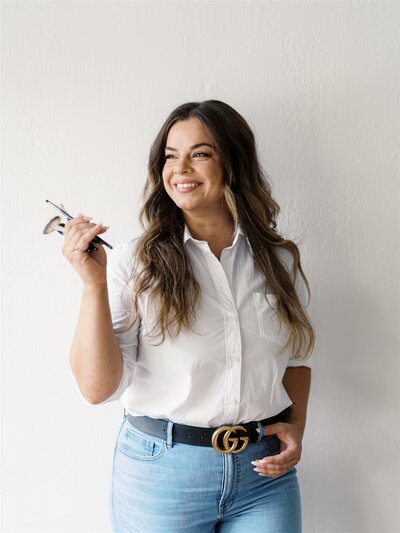 Brielle Brenner makeup artist posing and smiling while holding a bunch of makeup brushes