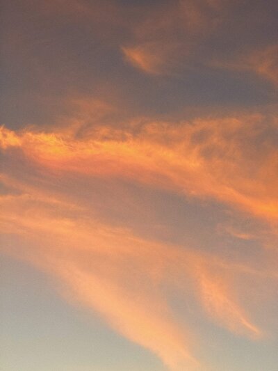 Soft orange and pink clouds at sunset against a light blue sky evoke the serene imagery found in Phillipa Leseberg's book, "His Name is Eric.