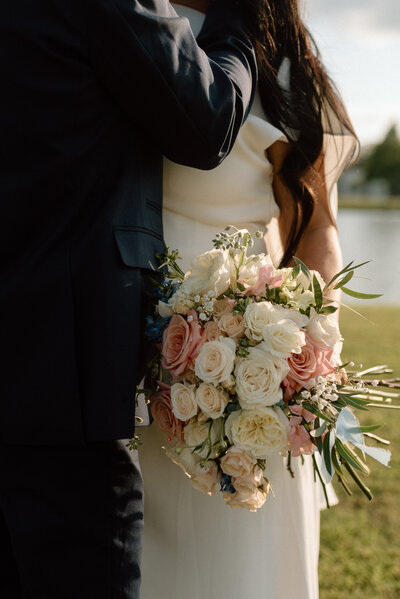 A beautiful wedding floral bouquet filled with pink, cream and peach roses with greenery. 