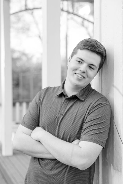 Senior boy leaning against building smiling