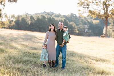 family photo of Tyler, TX family wearing neutral colors standing in front of lake