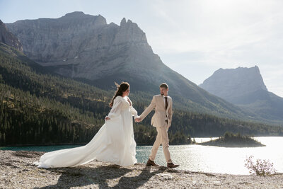 A couple sits on a rock and kisses in Glacier National Park at sunset.