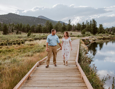 Couple walks hand in hand during their engagement session at Rocky Mountain National Park with Colorado wedding and portrait photographer.