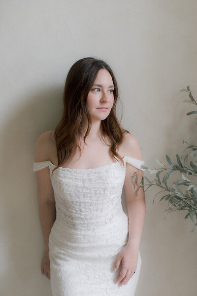 A bride leaning against the wall looking off to the side
