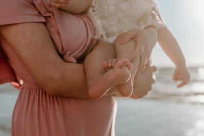 Mom holding her young child in from of her, while on the beach doing family photos in Corpus Christi, Texas.