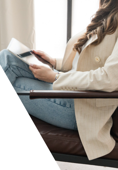 Dallas tax planning expert at Romo CPA Tax + Advisory using an iPad in her office while dressed in jeans and a beige blazer, creating strategic tax plans for clients.