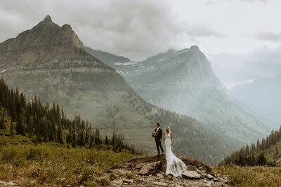 woman standing in front of mountains and holding her hair