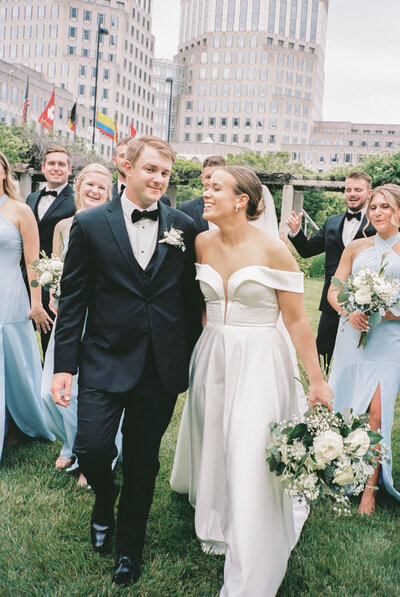 Two brides walking together through a downtown Cincinnati park, holding hands and laughing