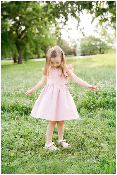 young girl twirling dress in outdoor tulsa family session with photographer Caroline Eidson