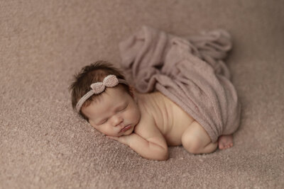 baby girl on pink backdrop at newborn photo session