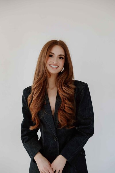 a female taking a branding photoshoot wearing a jean suit smiling with long red hair