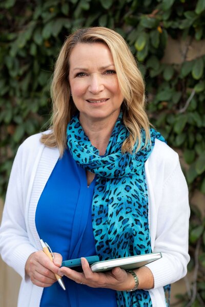 Grant writer Franciner smiling at camera in blue shirt, leopard blue scarf and white cardigan