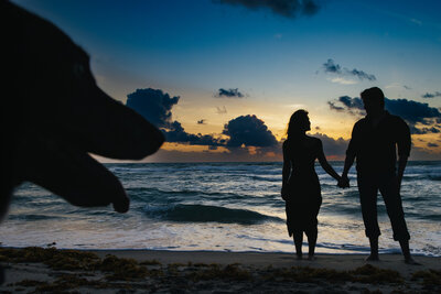 Silhouette of dog and couple at a sunrise beach session on the East coast.