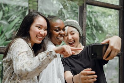 Women smiling and embracing outdoors, representing group coaching for anxious, high-achieving women ready to set boundaries and find community through shared healing.
