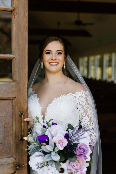 bridal portrait of bride in white wedding dress standing in chapel doors at Four Fifteen Estates in New Boston, TX