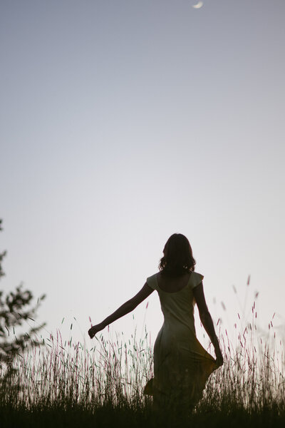 College senior wearing a flowing yellow dress, smiling confidently in natural outdoor light