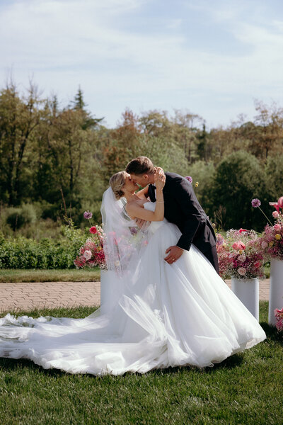 Vermont Wedding Photographer | Sincerely Liz Photography Documentary Wedding, Engagement, Elopement, Maternity and Newborn Photographer in New England | Bride and groom kiss in front of a pink themed floral arrangement