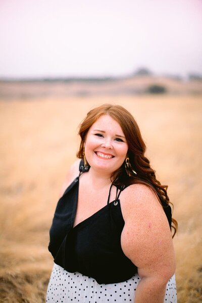Red haired white woman smiles in field 