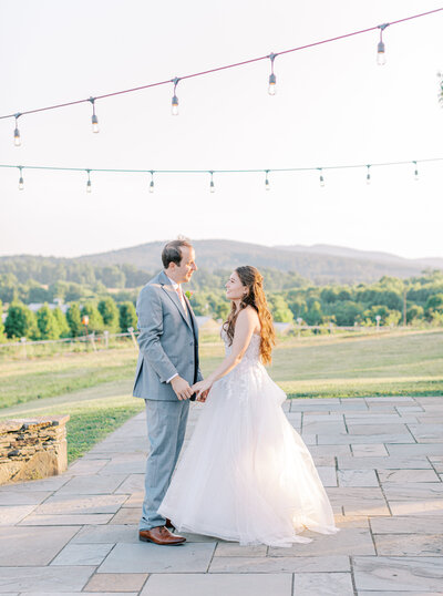 Charlottesville wedding photographer captures bride and groom’s first kiss after ceremony at Boxwood at Market at Grelen. Bride wearing hair in French braid. Orange florals decorates the ceremony space.