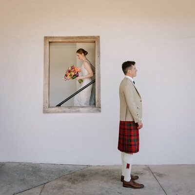 Bride walking down stairs in mirror and groom standing by  film wedding photographer Noble Photo Co