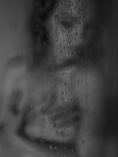 Vrouw in douche omringd door licht — intiem moment van me-time en zachtheid






