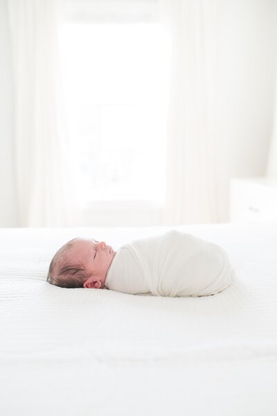 baby boy swaddled on bed