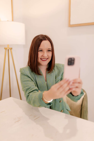 young woman with short brown hair smiling at camera phone