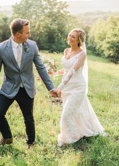 bride and groom holding hands walking in field