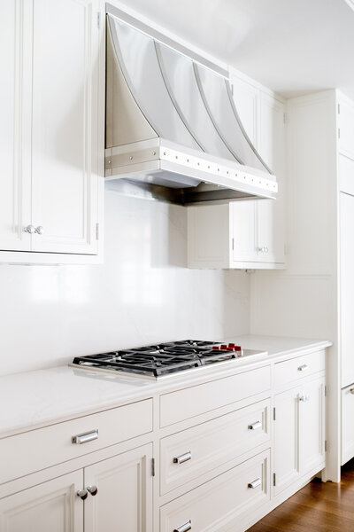 Transitional kitchen in Brookline featuring a stainless steel hood, white cabinetry, and warm wood accents