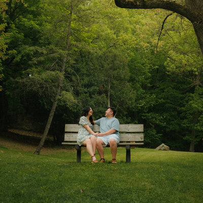 A photo of a couple sitting on the bench outside.