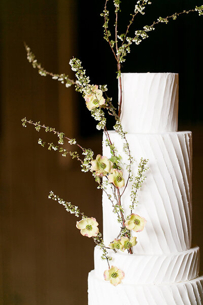 Elegant wedding cake with simple sweeping frosted tiers with organic floral branches.