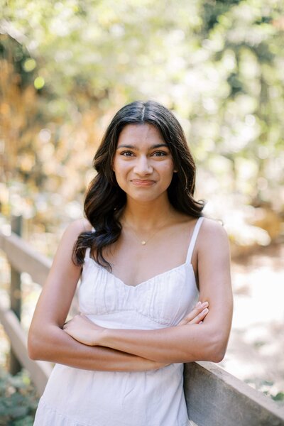 senior girl crossing her arms and leaning against a bridge and smiling with her mouth closed