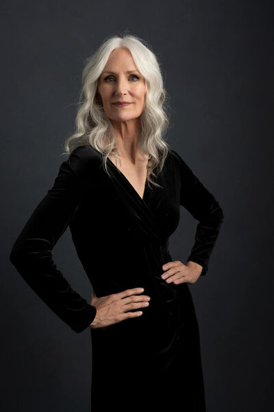 Silver hair woman is wearing an elegant black dress for her 50's birthday studio session
