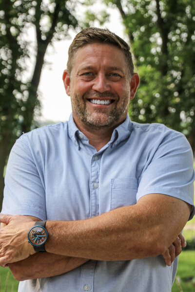 Jay Grommesch, the owner of Quality One Automation, is pictured standing confidently in an outdoor setting. Wearing a business-casual outfit, he embodies the professionalism and innovation that his company brings to the hospitality, corporate business, and multi-family residence sectors. His years of experience reflect his commitment to leveraging cutting-edge technology to enhance safety, security, and efficiency. Jay’s approachable demeanor and leadership skills are evident, making him a trusted expert in the industry.