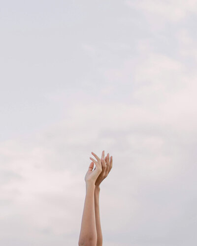 Frau hebt die Arme zum Himmel – Symbol für neues Lebensglück, Klarheit, Dankbarkeit und innere Stärke.
