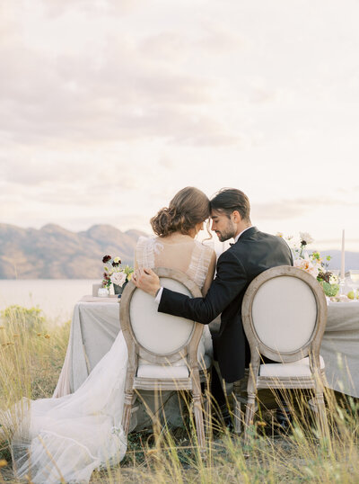 bride and groom sitting at alfresco wedding reception facing rolling hills