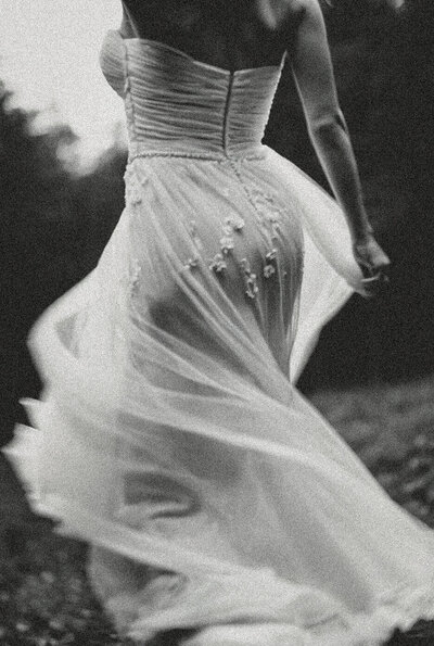 A woman in a strapless wedding dress runs outdoors, the skirt of her dress flowing behind her—capturing the creative spirit that inspires Sweet Pea Ink Creative’s brand design.